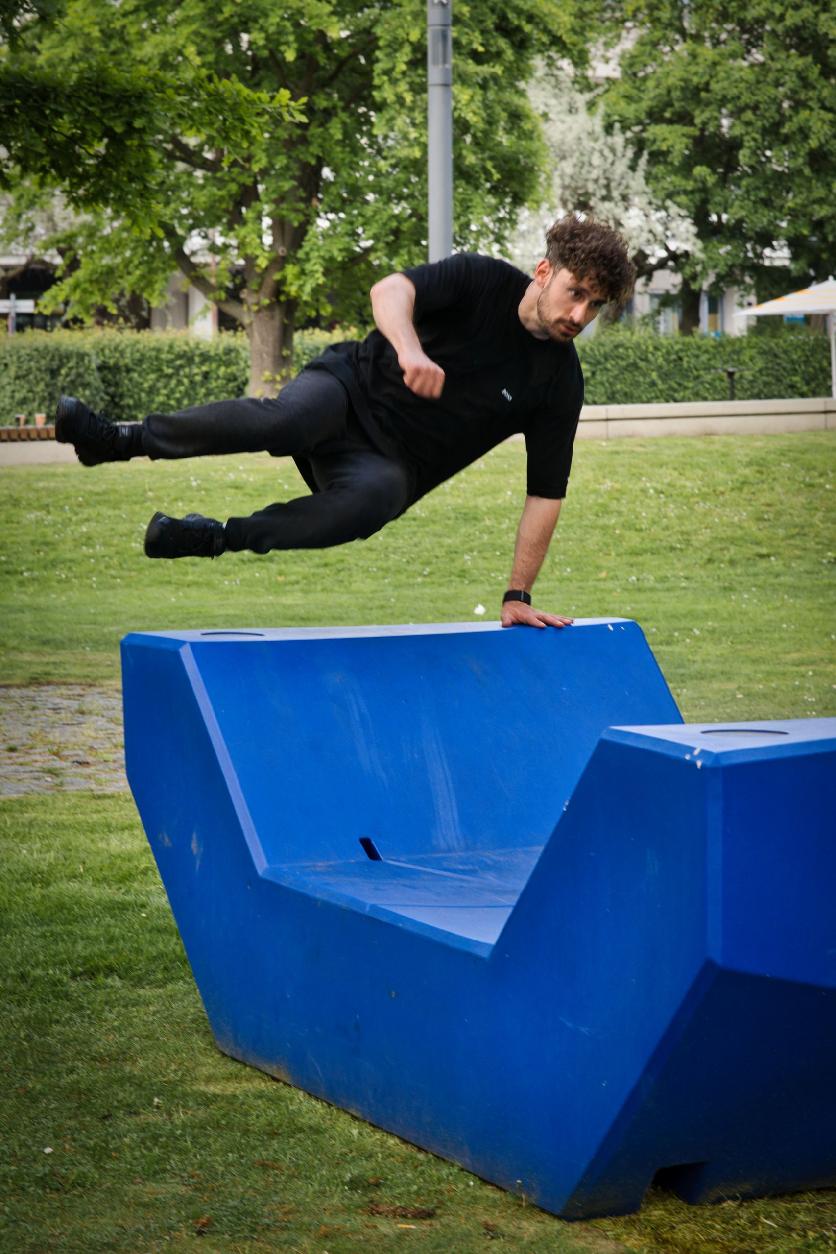 A man skillfully performing parkour on a blue structure in a Berlin park.